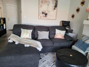 A living room with a grey sofa, patterned throw, and decorative pillows. - Room-charming Home in North Edmonton (Edmonton)