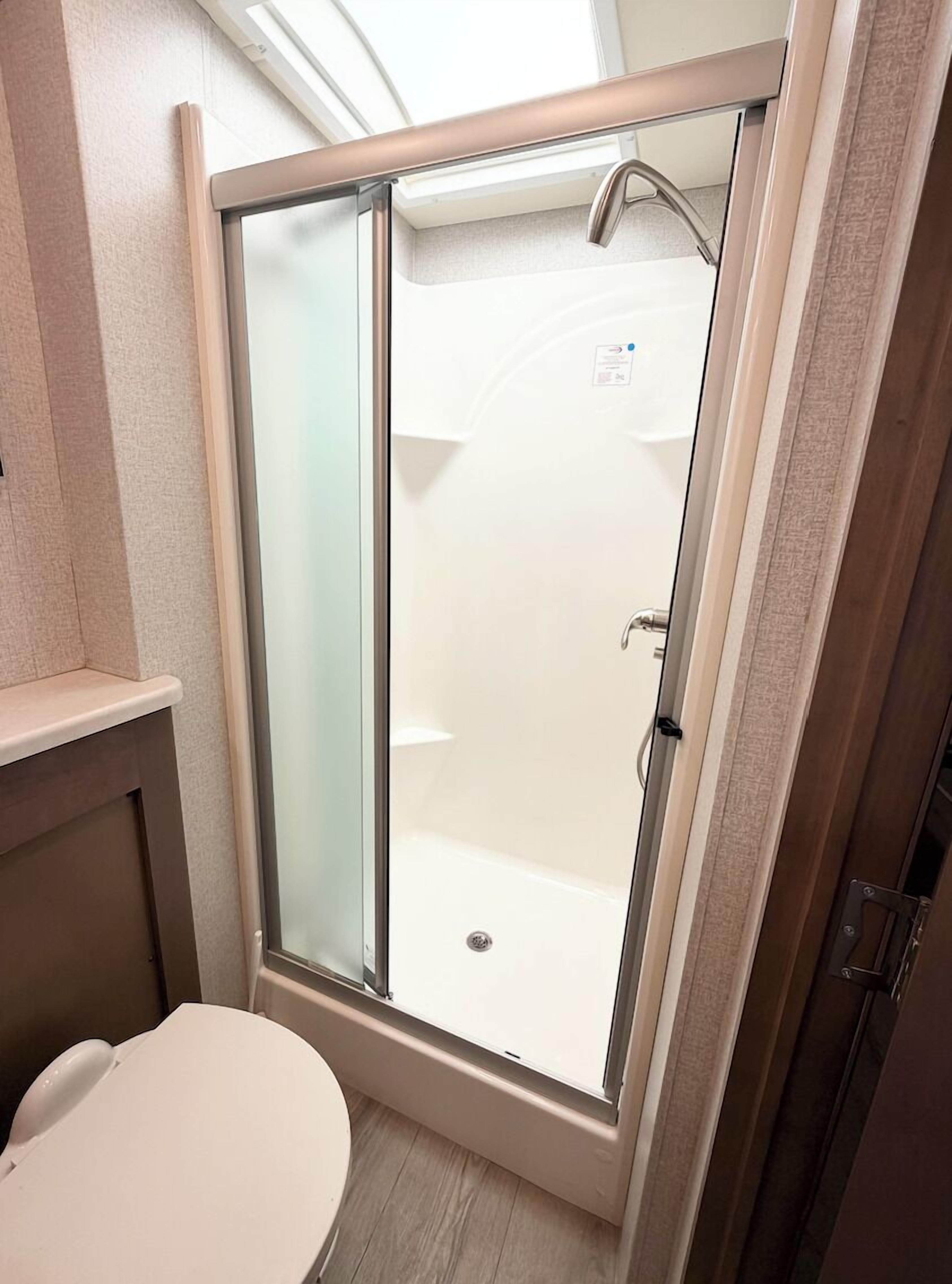 Une salle de bain avec une douche à parois de verre, des toilettes et un lavabo.