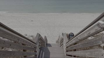 A wooden staircase leading to a beach with a clear view of the ocean.