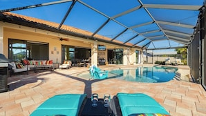 Ein überdachter Außenbereich mit Pool, Liegestühlen und einem Tisch mit Gläsern.
