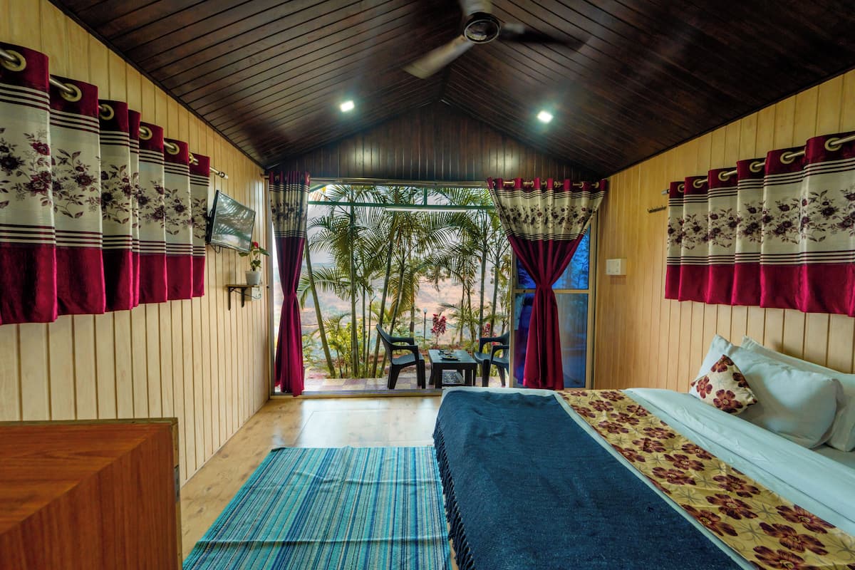 A room with a bed, a desk, and a view of palm trees.
