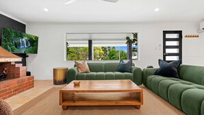 Una sala moderna con un sofá verde, una mesa de centro de madera y una chimenea.