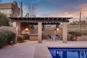 An outdoor patio with a pool, a pergola, seating, and a barbecue area. - NEW 6BR Carefree Estate with Views | Tennis, Pickleball, Pool, Infinity Spa, Golf & Views (Carefree)