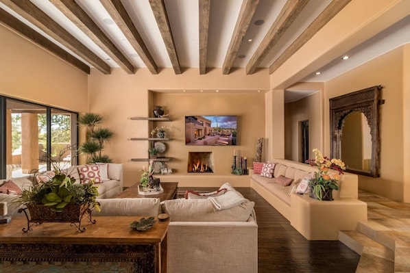 Un salón espacioso con chimenea, sofás, una mesa de centro y un televisor montado en la pared.