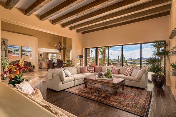 Ein geräumiges Wohnzimmer mit einem großen Sofa, einem Couchtisch und Blick ins Freie.