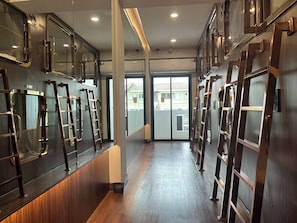 A corridor with mirrored walls, wooden flooring, and a view of the outside through a glass door. - The Rich Cafe & Hostel (Pattaya)