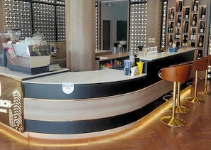 A modern bar area with a curved counter, a 'PICK UP HERE' sign, and a wine rack in the background. - The Rich Cafe & Hostel (Pattaya)