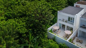 Una casa moderna con balcón, rodeada de abundante follaje.