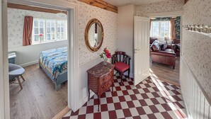 A room with a checkered floor, a bed with patterned bedding, a dresser, a chair, and a mirror on the wall. - Luxurious home in Gudhjem with WiFi (Gudhjem)