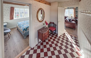A room with a checkered floor, a bed with patterned bedding, a dresser, a chair, and a mirror on the wall. - Luxurious home in Gudhjem with WiFi (Gudhjem)