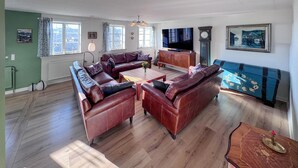 A living room with a sofa set, a television, a clock, and a painting on the wall. - Luxurious home in Gudhjem with WiFi (Gudhjem)