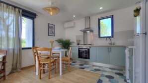 A modern kitchen with a dining area, featuring a stove, oven, and a large window.