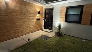 Een modern huis met een houten gevel, een zwarte deur en een kleine tuin.