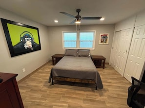 Un dormitorio con cama, ventilador de techo, ventana y puerta.