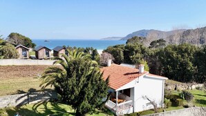 A coastal property with a white building, a red-tiled roof, and a view of the sea.