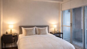 A modern bedroom with a large bed, two bedside tables with lamps, a chair, and a large window. - Modern Loft 1BD/1BA in King West (Toronto)
