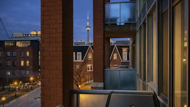 A balcony with a grill, a view of a cityscape, and a tower in the background. - Modern Loft 1BD/1BA in King West (Toronto)