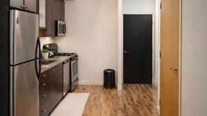 A compact kitchen with stainless steel appliances, a microwave, and a small trash bin. - Modern Loft 1BD/1BA in King West (Toronto)