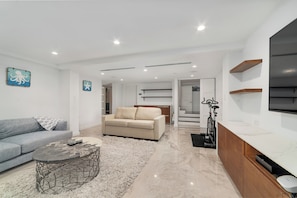 Una sala de estar moderna con sofá, mesa de centro y televisor.