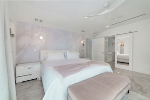 Un dormitorio moderno con una cama grande, mesitas de noche, un armario y un ventilador de techo.