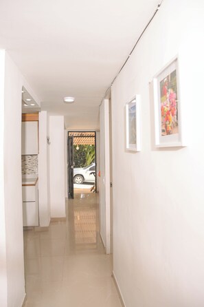 A hallway with a tiled floor, white walls, and framed pictures. - Beautiful accommodation with a view of Medellín (Medellín)