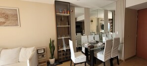 A modern dining area with a glass table, white chairs, and a mirrored cabinet with decorative items. - Charming 2-bedroom apartment in peaceful San Isidro neighborhood (San Isidro)