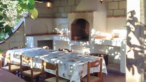 An outdoor kitchen with a brick oven, dining table, and chairs. - Lovely apartment in Ricadi with WiFi (Ricadi)