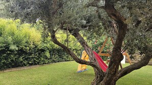 Un árbol con un tobogán rojo en un área con césped.