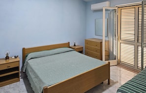 A bedroom with a bed, a nightstand, a dresser, a wardrobe, and a window with blinds. - Cozy apartment in Ricadi with swimming pool (Ricadi)