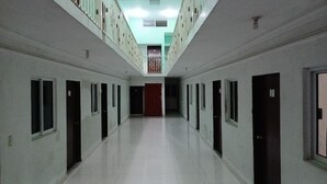 Un largo y estrecho pasillo con puertas a ambos lados, que conduce a un espacio central con una puerta roja al final.