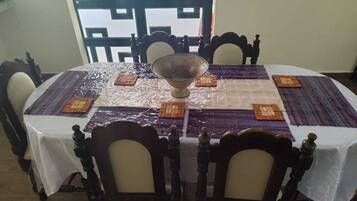 A round dining table with a white tablecloth, a central glass bowl, and patterned placemats.