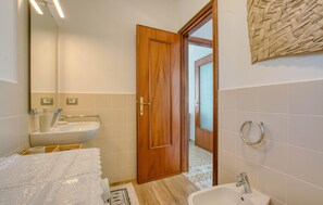 Ein Badezimmer mit Holztür, Waschbecken, Bidet und Spiegel.