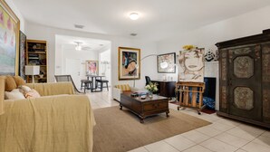 Ein Wohnzimmer mit Sofa, Couchtisch und Schrank. An der Wand hängt ein Bild und im Hintergrund steht ein Sessel.