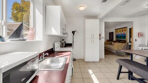 Une cuisine moderne avec des meubles blancs, un évier et un coin repas équipé d’une banquette.