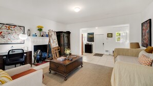 Un salon avec une cheminée, un canapé, une table basse et un tableau au mur.