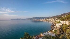 A coastal town with buildings along the waterfront, a clear sky, and calm sea.