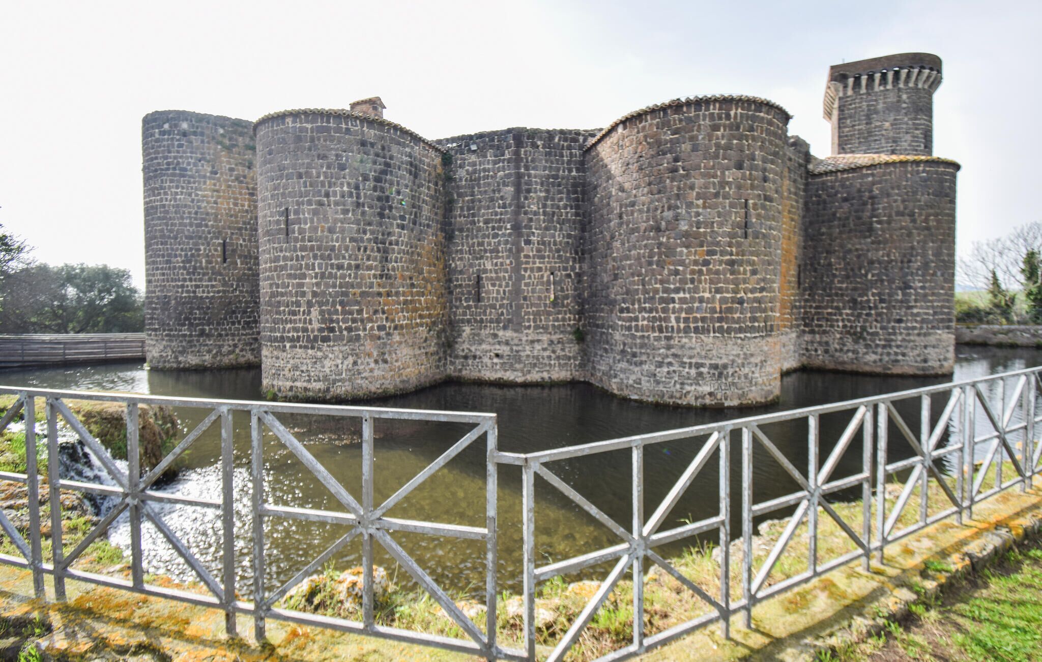 A large stone fortress with multiple cylindrical towers and a moat.