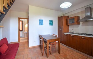 A compact kitchen with wooden cabinets, a dining table, and a red sofa. - 2 bedroom cozy home in Pescia Romana (Pescia Romana)