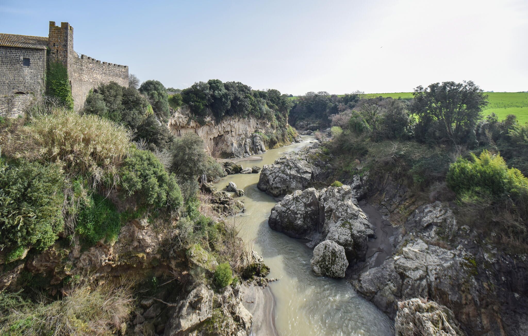 A river flowing through a rocky gorge with a castle on the left.