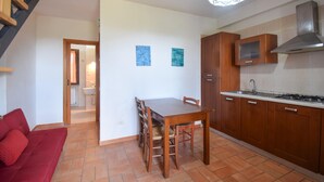 A compact kitchen with wooden cabinets, a dining table, and a red sofa. - Stunning home in Pescia Romana with swimming pool (Pescia Romana)