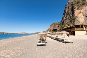 A beach with sun loungers and a thatched-roof building. - Sea View - 40 Parallelo - Deluxe 25, Marina di Camerota, Italy (Marina di Camerota)