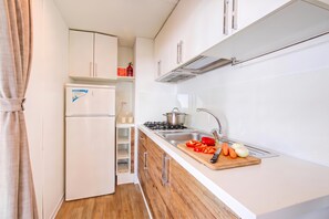 Een kleine keuken met witte kastjes, een inbouwfornuis en een houten aanrecht.
