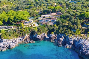 A coastal property with multiple villas, rocky cliffs, and clear turquoise waters. - Sea View - 40 Parallelo - Deluxe 25, Marina di Camerota, Italy (Marina di Camerota)