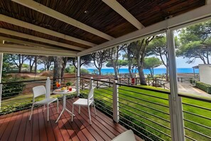 Un espace extĂ©rieur abritĂ©, dotĂ© dâune table et de chaises, offrant une vue sur la mer et agrĂ©mentĂ© dâune pelouse bien entretenue.