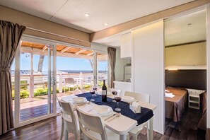 Una zona de dinar moderna amb taula preparada per a dues persones, vista cap a l'exterior i una altra zona de dinar separada.
