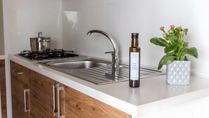 A kitchen with a stainless steel sink, a gas stove, wooden cabinets, and a potted plant. - Sea View - 40 Parallelo - Deluxe 21, Marina di Camerota, Italy (Marina di Camerota)