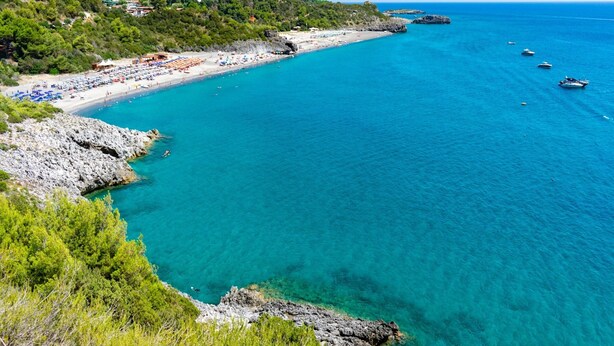 A coastal beach with clear turquoise waters, rocky cliffs, and a few boats. - Sea View - 40 Parallelo - Deluxe 21, Marina di Camerota, Italy (Marina di Camerota)