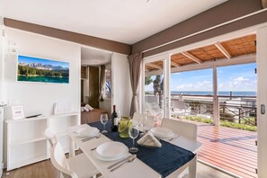 A dining area with a table set for two, a view of the sea, and a mountain landscape on the wall. - Sea View - 40 Parallelo - Deluxe 21, Marina di Camerota, Italy (Marina di Camerota)