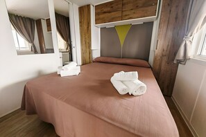 Une chambre d’hôtel avec un lit, une tête de lit en bois et une fenêtre avec des rideaux.