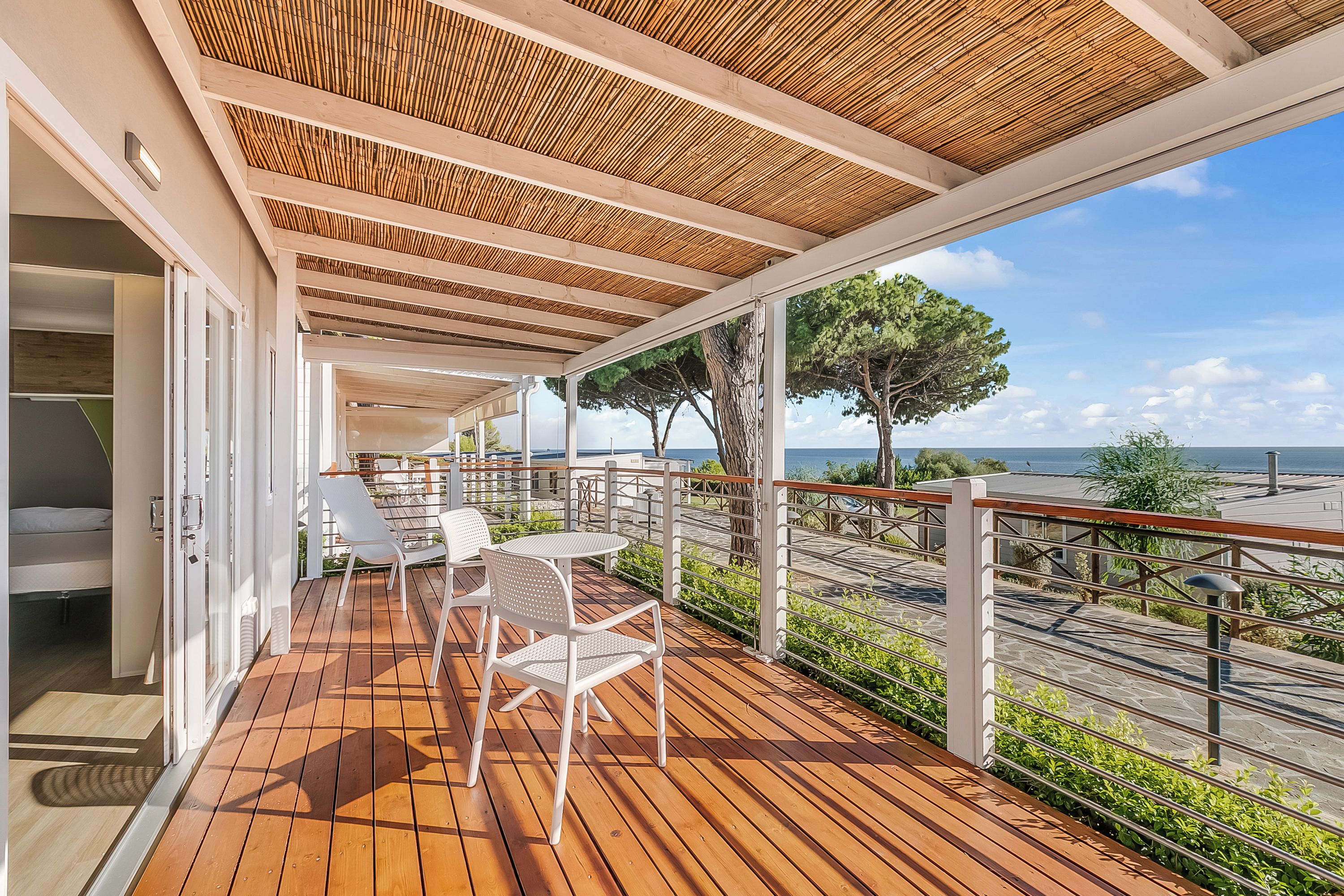 Una terraza de madera con mobiliario exterior y vista al mar.